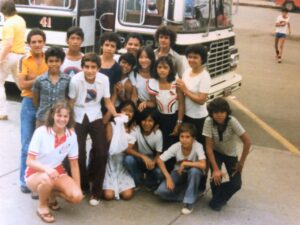 Group of students in 1980 posing in front of a bus